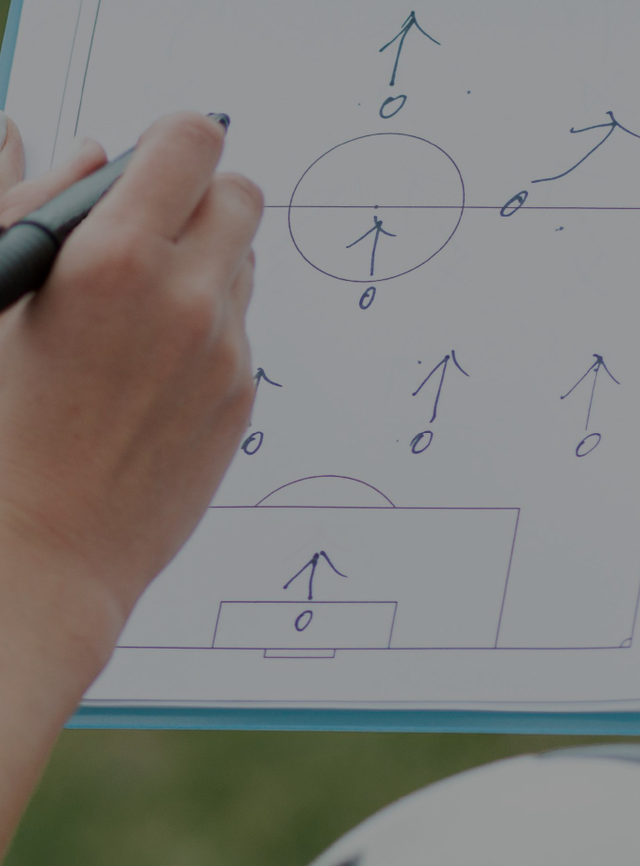 Mãos a segurar uma folha com desenho sobre técnicas de futebol