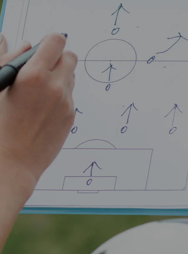 Mãos a segurar uma folha com desenho sobre técnicas de futebol