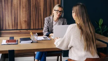 Duas colegas de trabalho sentadas uma em frente da outra