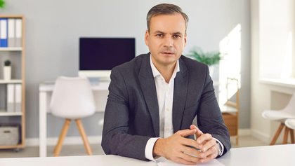 retrato de un analista político sentado en una oficina, mirando a cámara y escuchando
