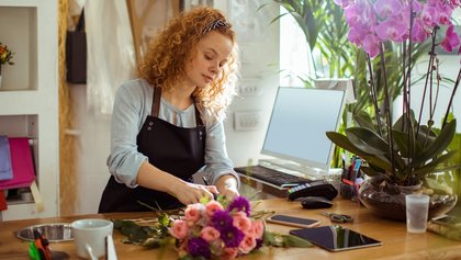 chica joven hace un ramo de flores en una floristería