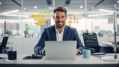 gestor administrativo sonriente sentado frente a su ordenador portátil