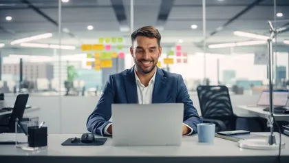 gestor administrativo sonriente sentado frente a su ordenador portátil
