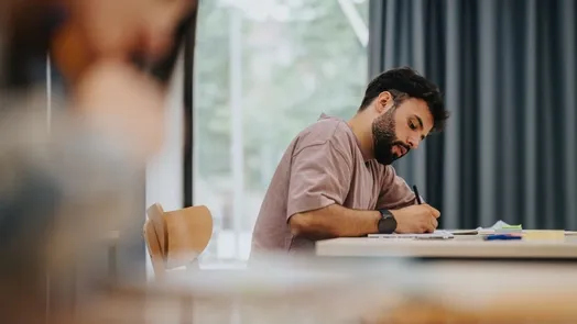 estudiante está concentrado escribiendo en un aula