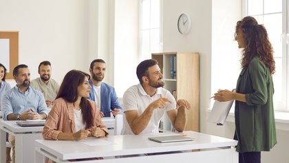 Grupo de adultos numa sala de aula a ouvir atentamente uma formadora.