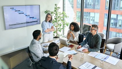 Equipa de profissionais em reunião de planeamento com gráfico projetado no ecrã.